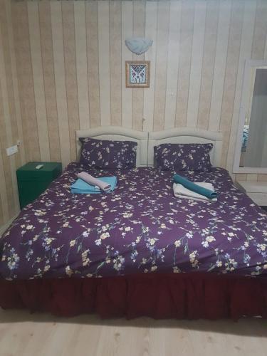 a bed with purple sheets and blue pillows at Saklı Bahçe Pension in Cıralı