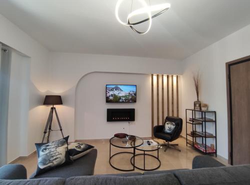 a living room with a couch and a tv on the wall at Grey Swan - Modern & Stylish apartment with Private Parking in Volos