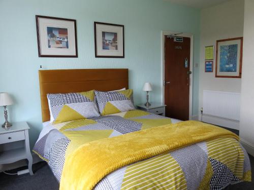 a bedroom with a large bed with a yellow blanket at Ainsley Court Guest House in Scarborough