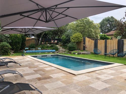 - une piscine avec un parasol dans la cour dans l'établissement Le Numéro 15, à Saint-Seurin-sur-lʼIsle