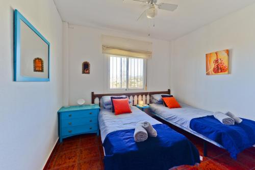 twee bedden in een kamer met blauwe en oranje kussens bij Casa Acacia in Nerja