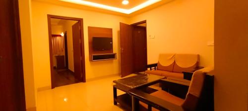 a living room with a couch and a table at Hotel Rhythm Grand Suite in Tiruchchirāppalli