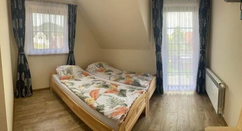 een klein bed in een kamer met 2 ramen bij Pokoje u Basi in Sromowce Niżne