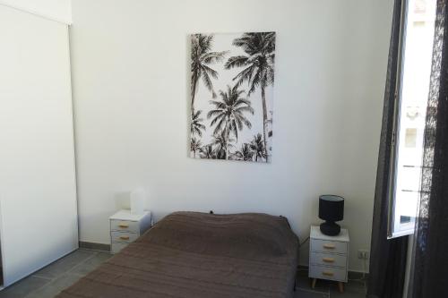 a bedroom with a bed and a picture of palm trees at Maison Carrée/Coeur historique de Nîmes - Superbe Appt 55m² in Nîmes