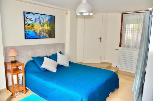 a blue bed in a white bedroom with a blue blanket at Le Jardin Paris in Ivry-sur-Seine