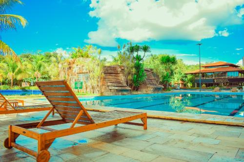 a wooden chair sitting next to a swimming pool at Ecologic Ville Resort - Oficial in Caldas Novas