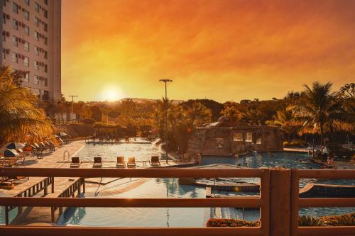 カルダス・ノバスにあるEcologic Ville Resort - Oficialの夕日を背景に見えるリゾートのプール