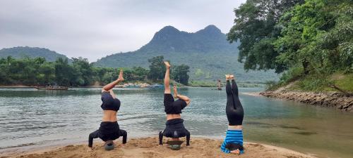 a group of people doing yoga on the shore of a river at Carambola Bungalow in Phong Nha
