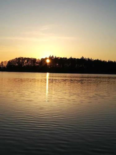 a sunset over a body of water with the sun setting at Apartment in ruhiger Wohnlage Sie sind in 3 Minuten am Trebbower See oder in 30 Minuten an der Ostsee in Klein Trebbow