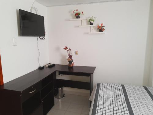 a bedroom with a desk and a tv and a bed at Hostal Dante in San Gil