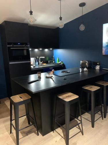 une cuisine avec un grand îlot noir et des tabourets dans l'établissement Adorable guest house au calme à 3 min du port, à Vannes