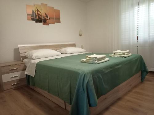 a bedroom with a bed with a green blanket at Apartments Vodarić Loznati in Cres