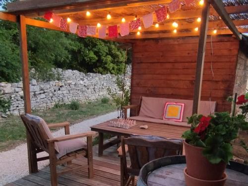 une terrasse en bois avec une table et une pergola éclairée dans l'établissement Au Pied du Mur, à Orgnac-lʼAven