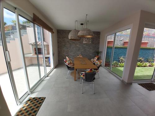 uma sala de estar com uma mesa, cadeiras e janelas em Banda Do Sol Self Catering Cottages em Estreito da Calheta