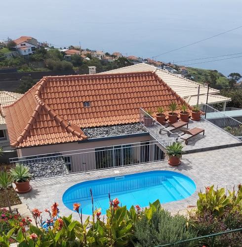 a house with a swimming pool and a roof at Banda Do Sol Self Catering Cottages in Estreito da Calheta