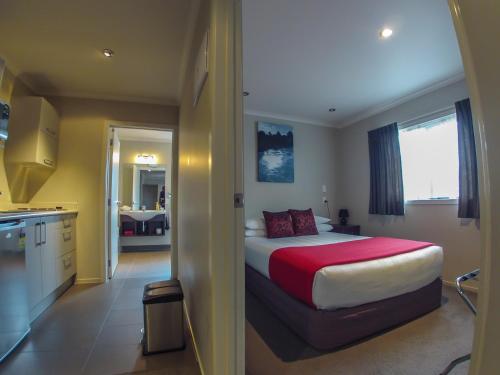 a bedroom with a large bed and a kitchen at Albert Court Motor Lodge in Hamilton