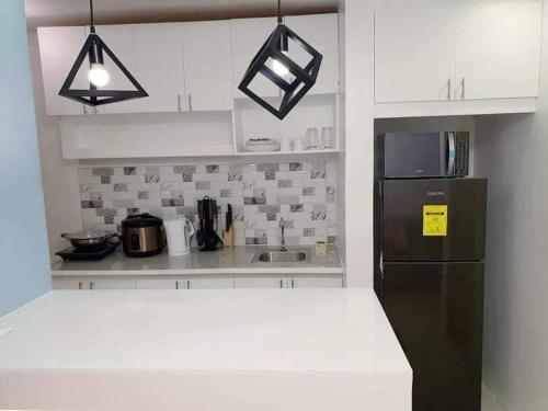 a kitchen with white cabinets and a black refrigerator at Cozy Boo Suite near Enchanted kingdom by Dynel in Santa Rosa