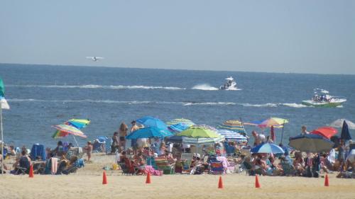 a crowd of people on a beach with umbrellas at Sea Girt Lodge in Sea Girt