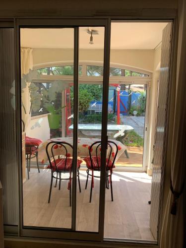 une porte en verre menant à une terrasse avec une table et des chaises. dans l'établissement Appartement jardin Cap d'Agde, au Cap d'Agde
