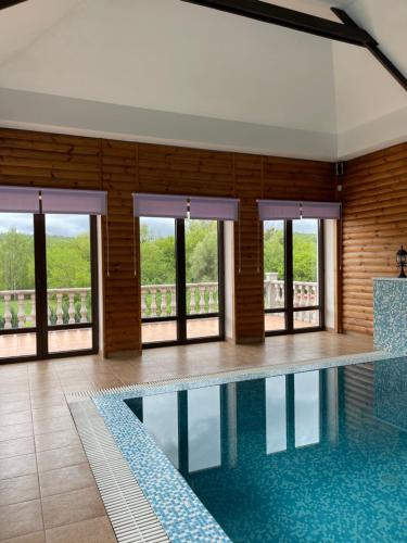 a swimming pool in a building with windows at Приватний будинок для сімейного відпочинку з басейном і сауною in Hryhorivka