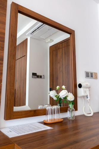 a mirror on a table with flowers in a room at Simon Hotel in Nha Trang