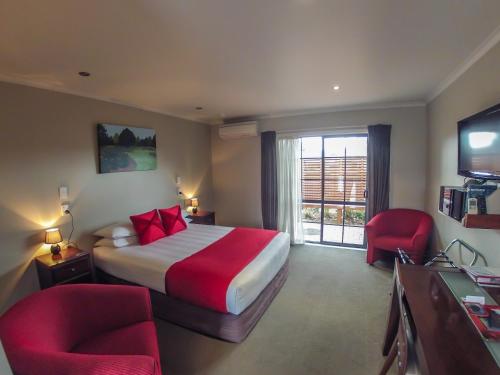 a hotel room with a bed and two chairs at Albert Court Motor Lodge in Hamilton