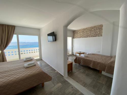 a hotel room with two beds and a balcony at Aeolos Bay Tinos in Tinos Town