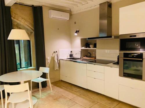 une cuisine avec des armoires blanches et une table avec des chaises dans l'établissement Studio de l'Atelier d'Artiste, à Avignon