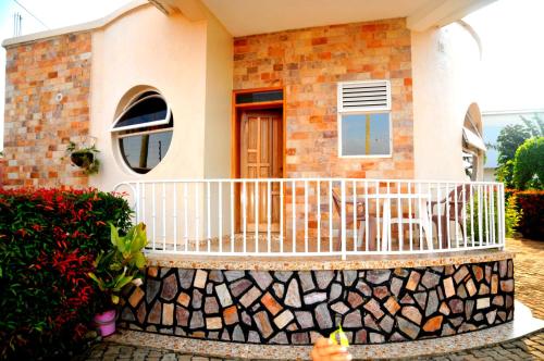 a house with a balcony with a stone fence at Victoria Lake View Guesthouse & Safaris in Entebbe