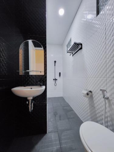 a black and white bathroom with a sink and a mirror at Grand Plaza Boutique Hotel in Karawang