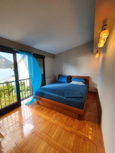 a bedroom with a blue bed and a large window at La Grande Apartments in Kotor