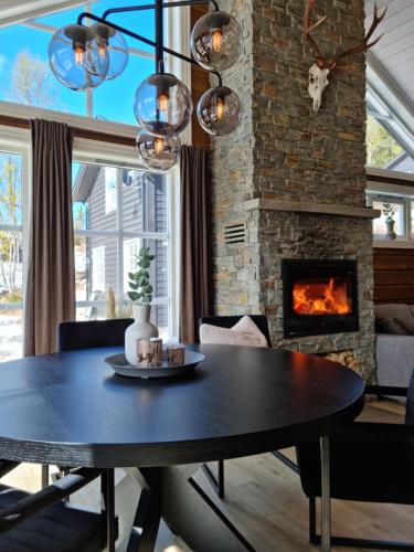 a dining room with a table and a fireplace at Fosskamben Panorama Sogndal in Sogndal