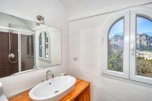ein weißes Badezimmer mit Waschbecken und Fenster in der Unterkunft DENTECALA 4 in Capri