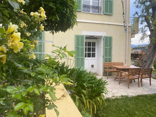 ニースにあるAppt avec jardin et clim proche Arènes de Cimiezの緑のシャッターとテーブルと椅子が備わる家