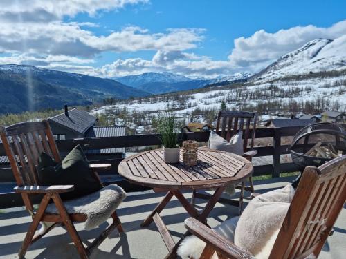 a patio with a table and chairs and mountains at Fosskamben Panorama Sogndal in Sogndal