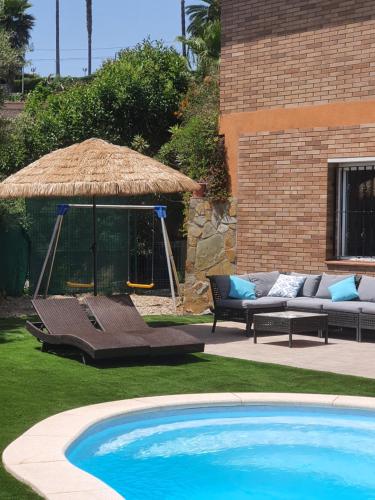 ein großer Pool mit einem Strohschirm und einem Sofa in der Unterkunft Vivalavida playa 1km in Lloret de Mar