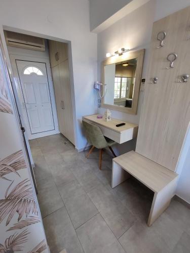 a bathroom with a sink and a desk and a mirror at Studios Apollon in Chrysi Ammoudia