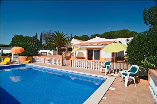 a swimming pool with chairs and umbrellas next to a house at 609 Villa Mariposa in Lagos