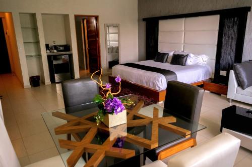 ein Hotelzimmer mit einem Bett und einem Tisch mit Blumen darauf in der Unterkunft Hotel Aquetzalli in Cocoyoc
