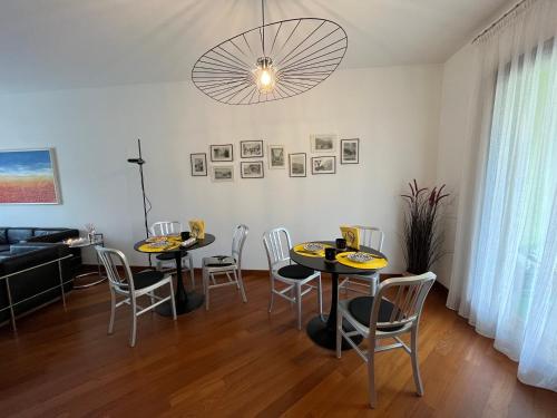 a dining room with two tables and chairs and a chandelier at Miss Scola Pastry Rooms - Lake Como in Abbadia Lariana