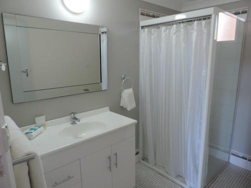 a bathroom with a sink and a shower with a mirror at Sussex Shores in Sussex Inlet