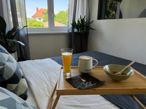 a table with a glass of orange juice on a bed at Designapartment Blue Sky -55m2-free parking & wifi in Graz