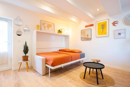 a bedroom with a bed with orange sheets and a table at Appartement cocooning proche mer in Carqueiranne