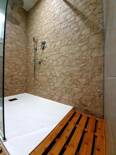 a shower in a room with a stone wall at Santos LODGE surf - 5 minutes walking to Praia da Rocha in Portimão