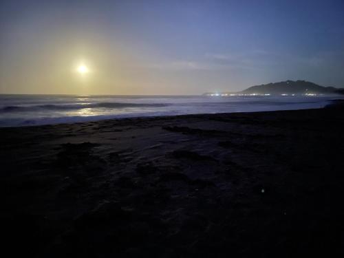 a beach at night with the sun rising over the ocean at Perla Negra Beachfront in Puerto Viejo