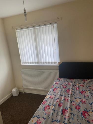 a bedroom with a bed and a window with blinds at 8 Challanor road in Yarm