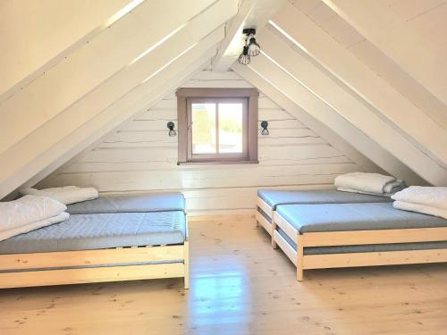 two beds in a attic room with a window at KOPUVA in Nidden