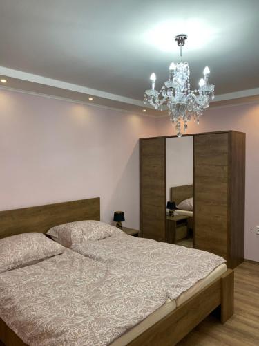um quarto com uma cama grande e um lustre em Csengődi Csecske Panzió em Csengőd