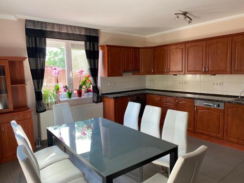 a kitchen with a glass table and white chairs at Csengődi Csecske Panzió in Csengőd