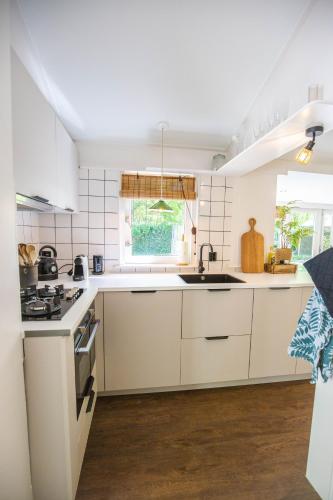 a white kitchen with a sink and a stove at Boshuisje op de Veluwe in Nunspeet